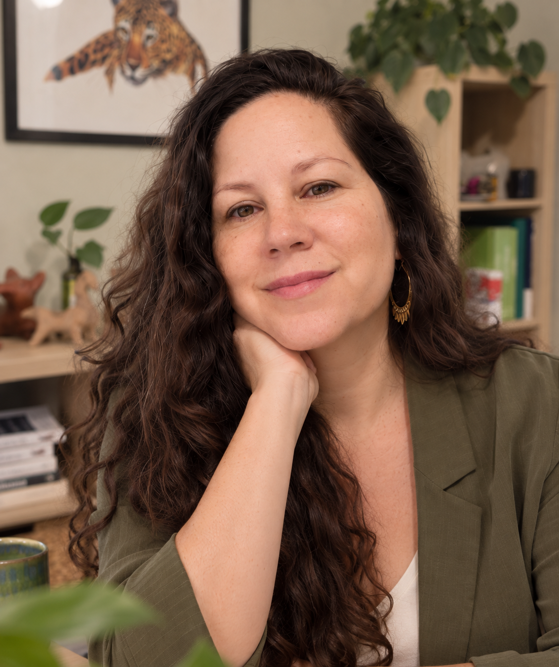 Alejandra Salazar Dreja, consultora en subvenciones para organizaciones ambientales, sonriendo en su oficina junto a plantas y un cuadro de un jaguar.